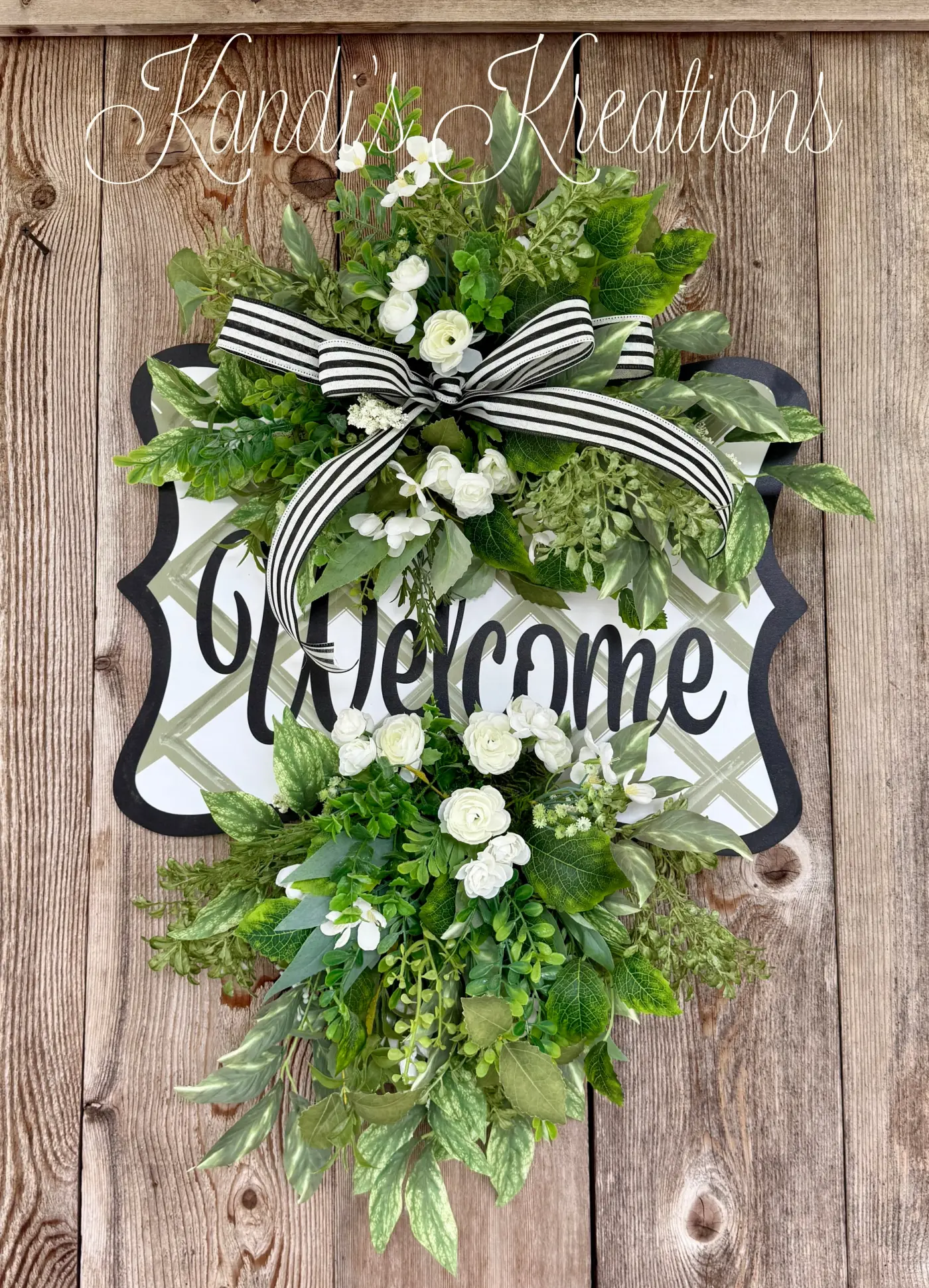 An elegant greenery welcome door hanger with white florals on a front door