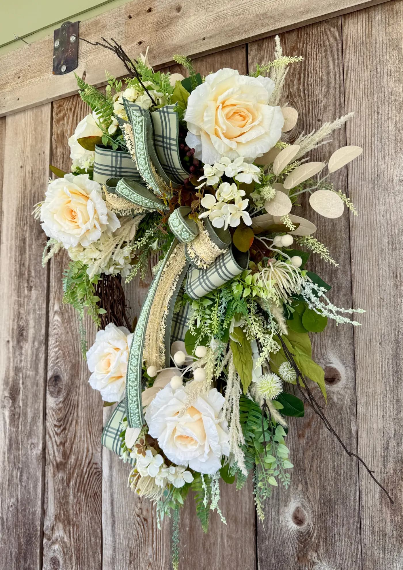 Close-up of an elegant cream rose grapevine wreath with lush greenery